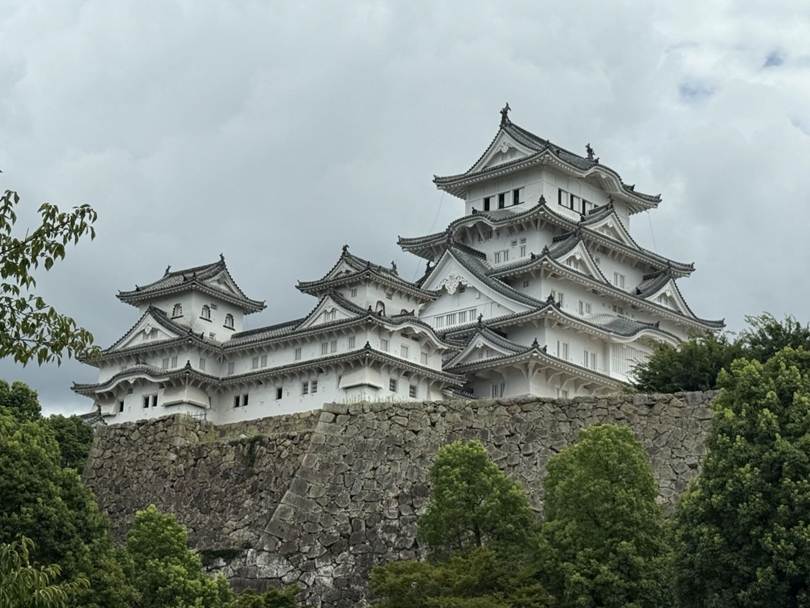 A white building on a rock wall with Himeji Castle in the background

AI-generated content may be incorrect.