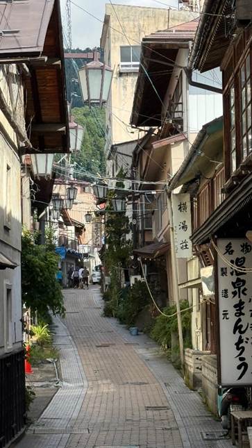 A narrow street with buildings and trees

AI-generated content may be incorrect.