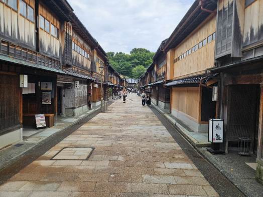 A street with buildings and people walking

AI-generated content may be incorrect.