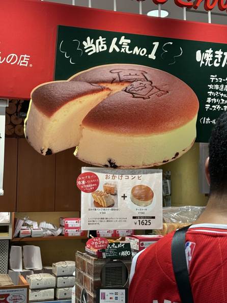 A person standing in front of a sign with a cake cut out

AI-generated content may be incorrect.