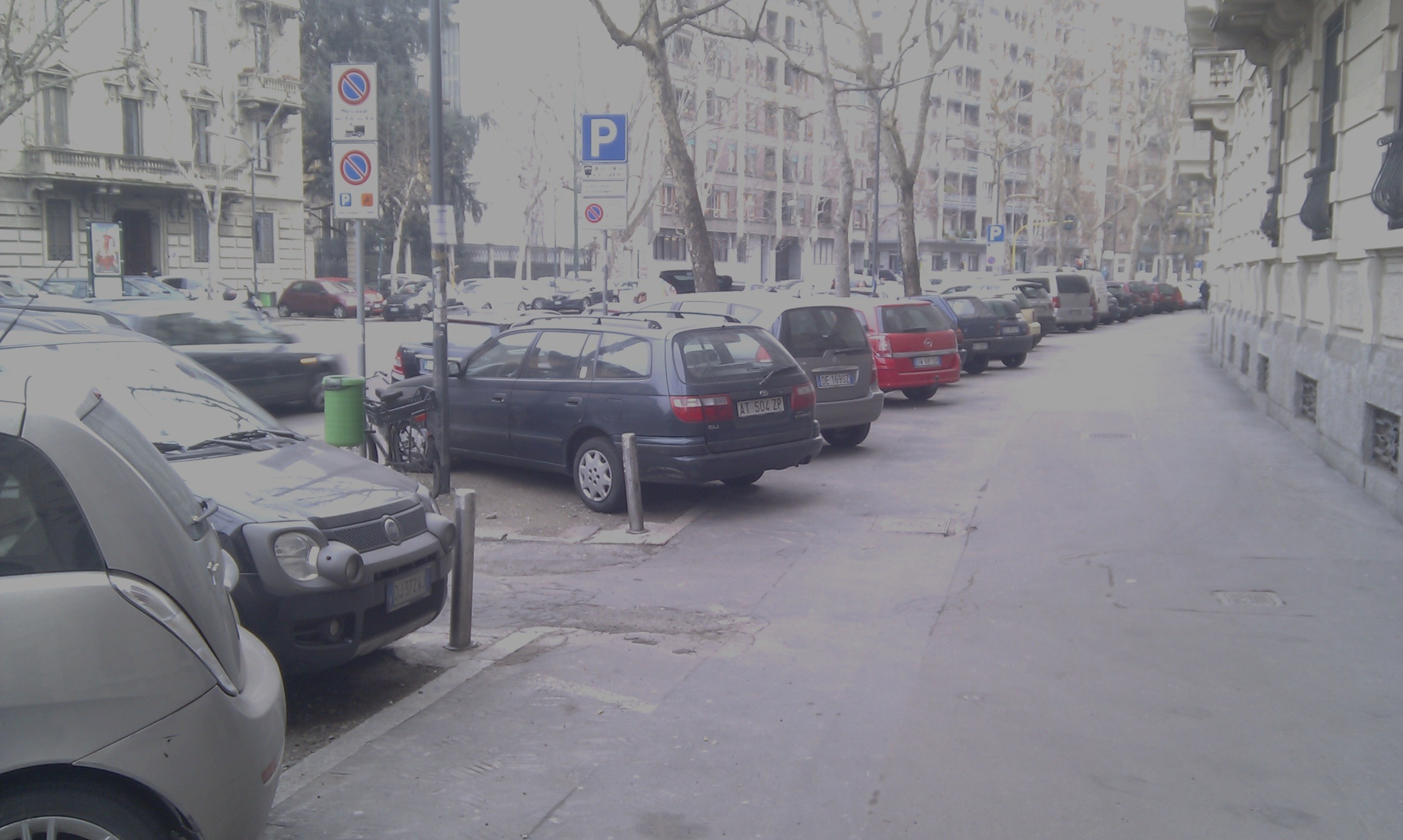 Central Milan street, cars parked along the pavement