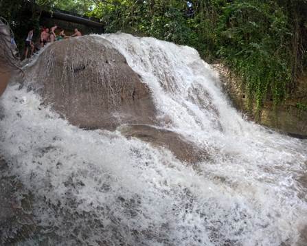 A waterfall with people standing on a rock

AI-generated content may be incorrect.