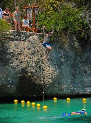 Someone jumping off a rope swing into the water at Xel-Ha
