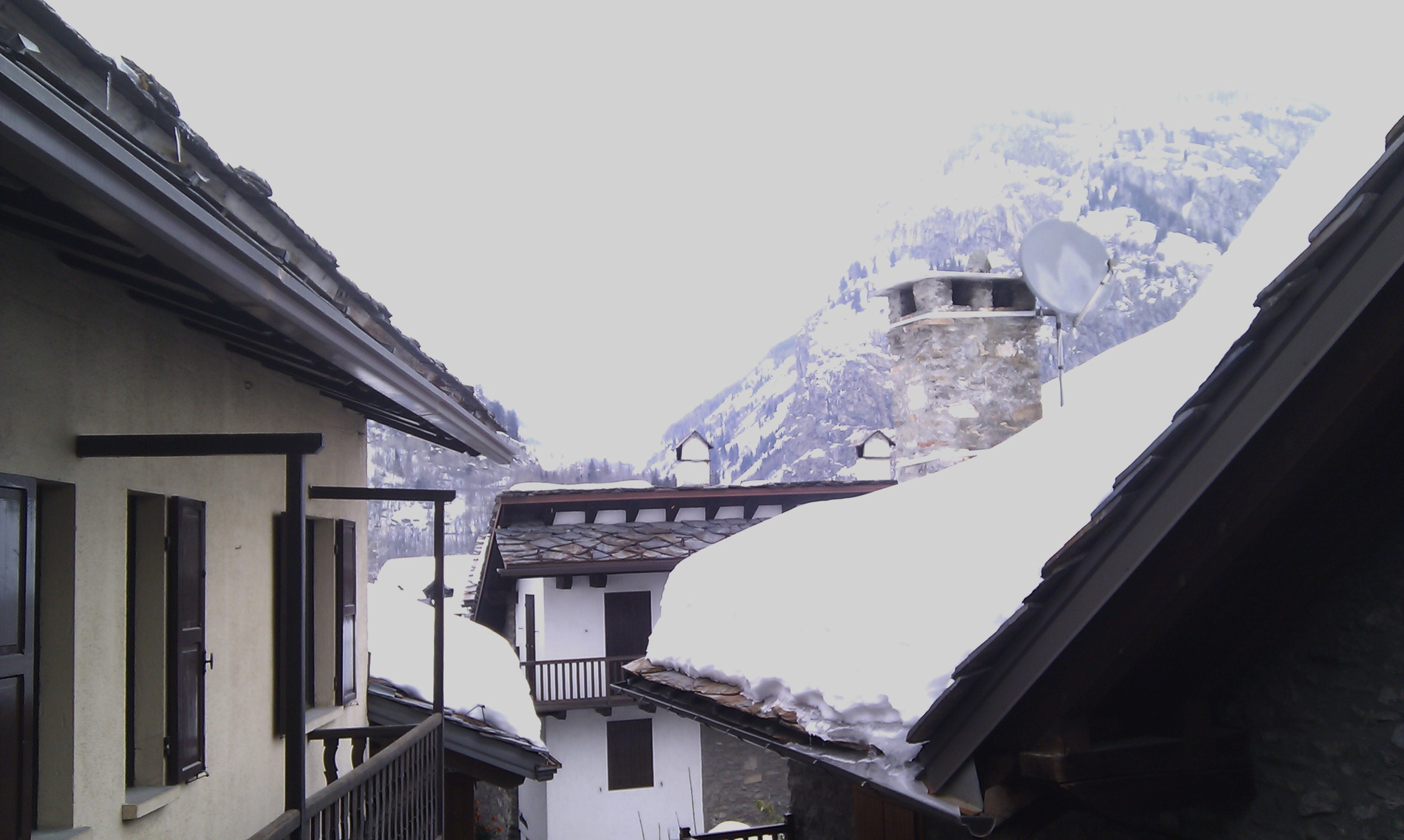 Rooftops of Courmayeur with misty mountains behind
