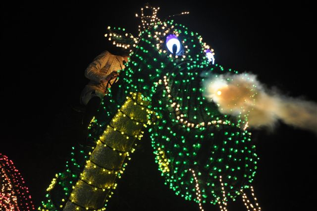 Illuminated dragon float breathing fire in the parade