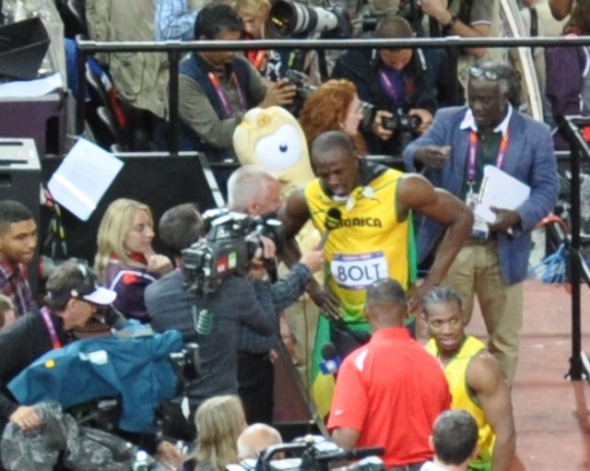 Usain Bolt with the Wenlock mascot and photographers trackside